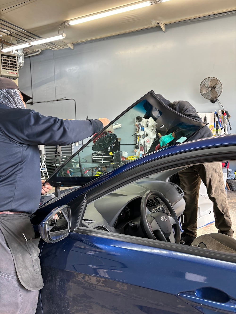 installing a new windshield on blue car