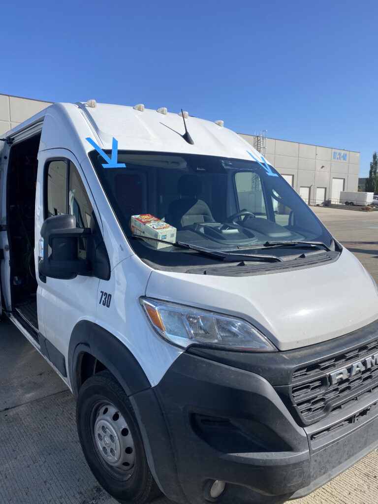White Ram commercial van with two blue arrows pointing to the windshield, highlighting professional auto glass repair.